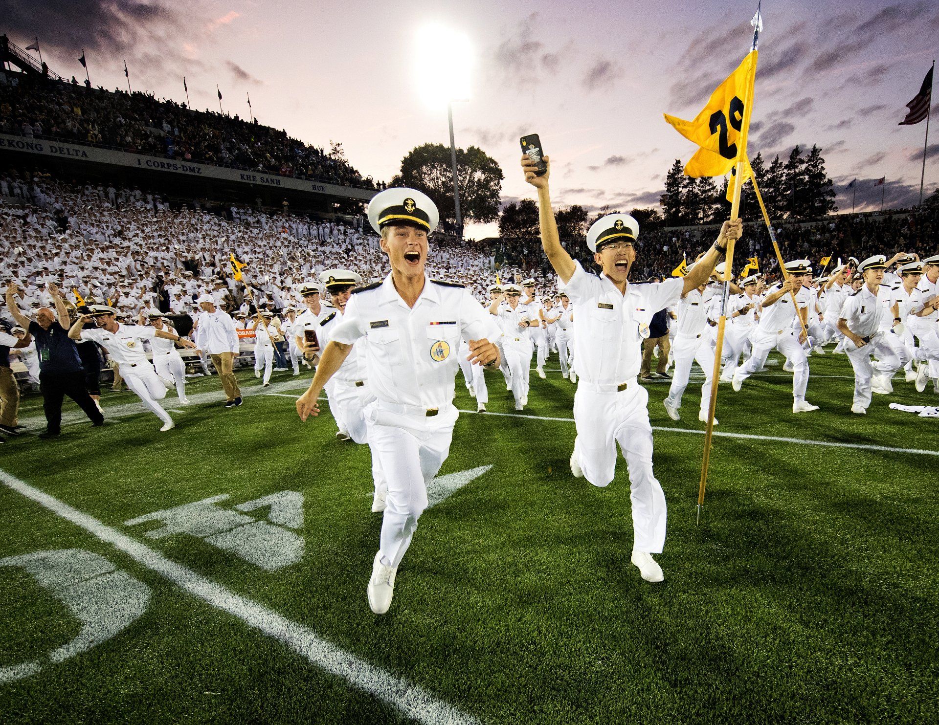 Naval cadets run on the field during a Navy vs Air Force football game