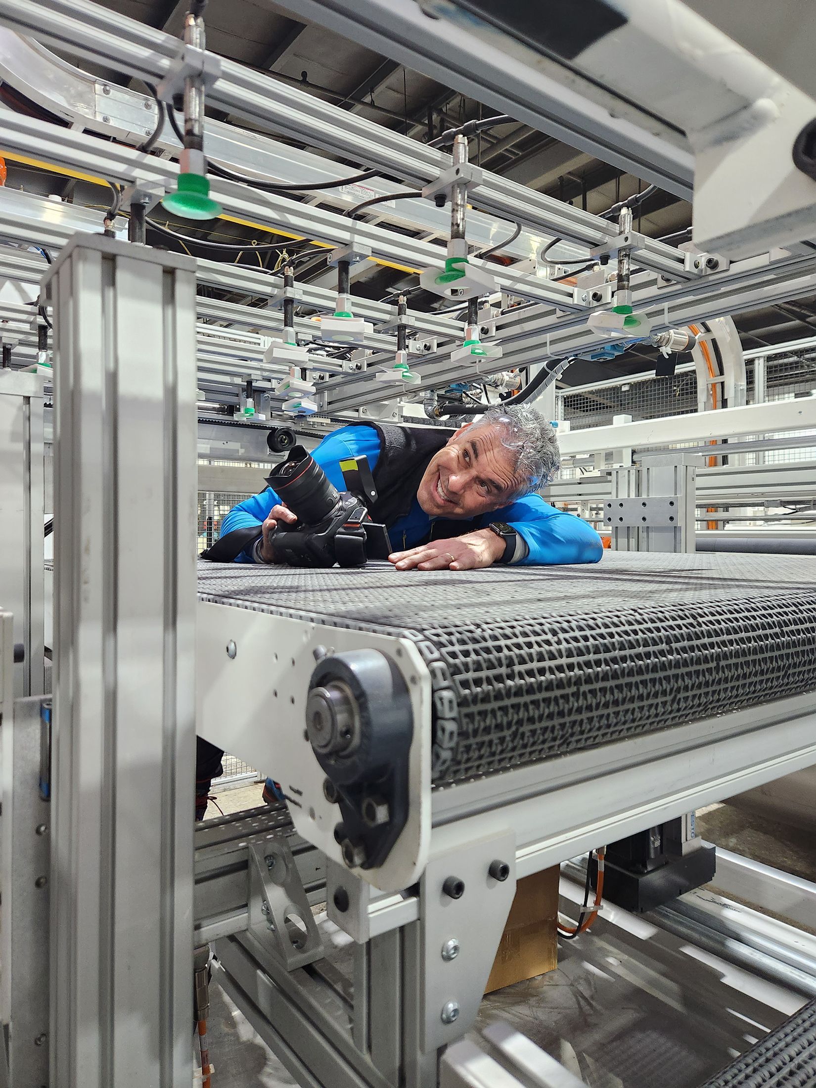 A commercial photographer climbs into the mechanics of an assembly operation at a manufacturing facility. The photographer is trying to make photos from the interior of the assembly line.