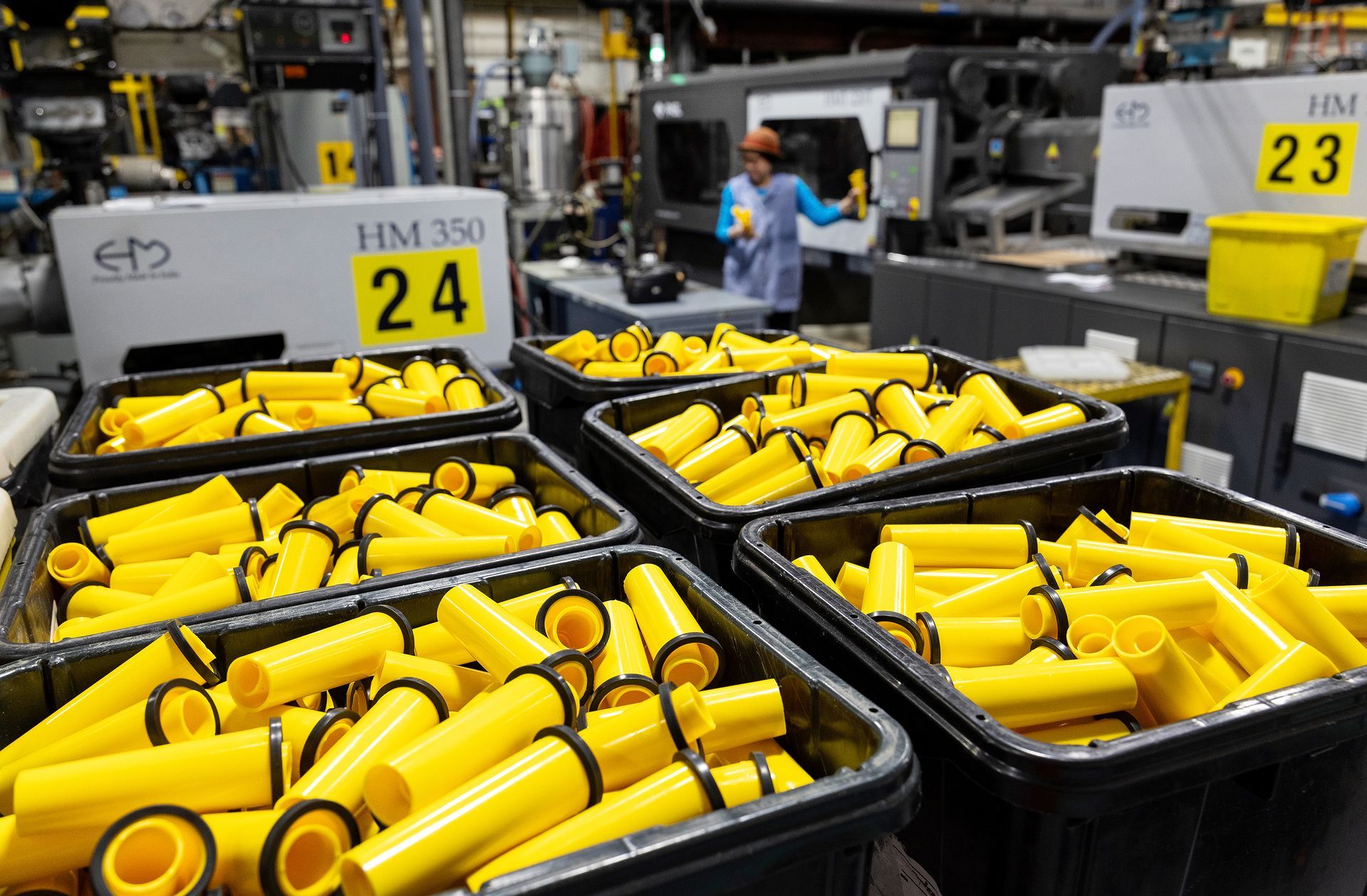 Bright yellow plastic nozzels fill bins in a plastics manufacturing facility.