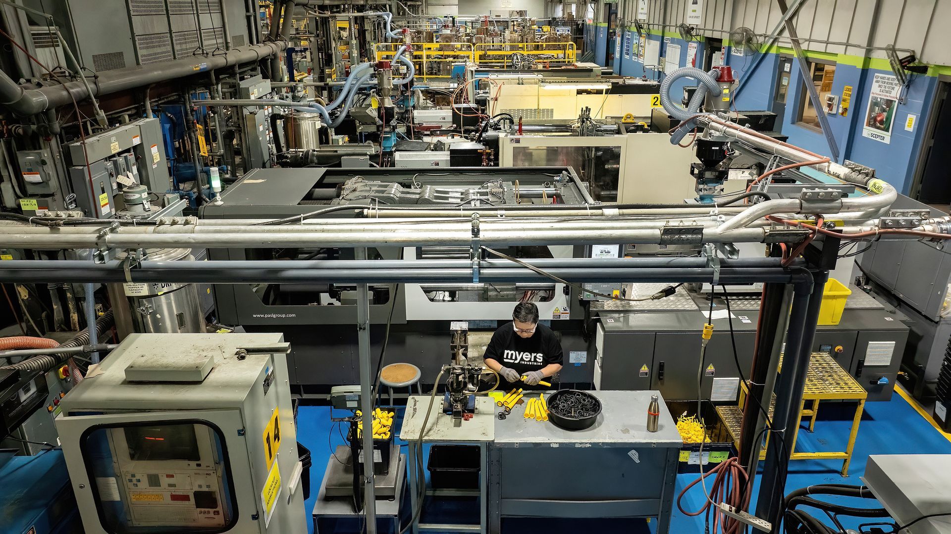 A woman in a plastics manufacturing plant assembles components. Photographer used a drone to take the photo from a distance and from overhead. 