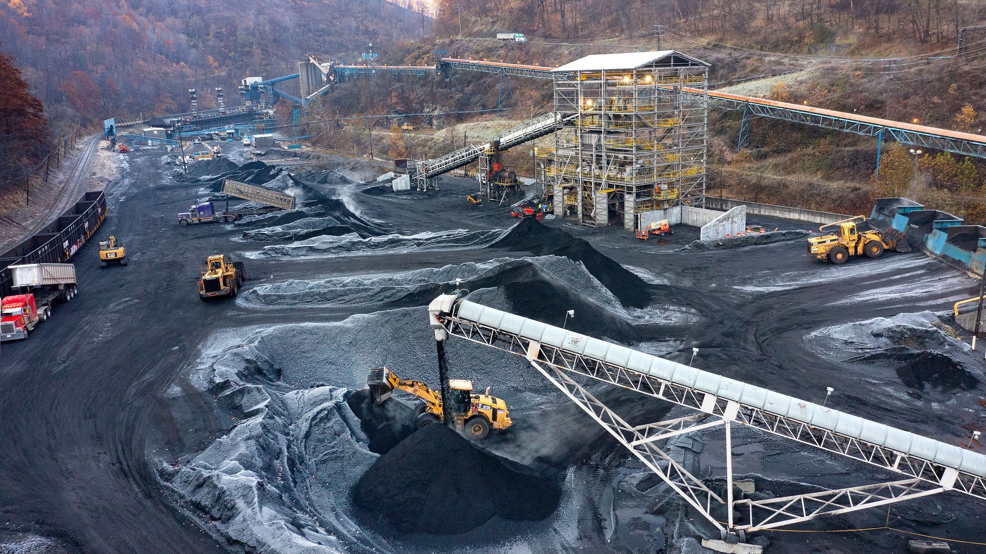 Loader machines move coal and coke product around an industrial facility during operations. Photographer used a drone to show the size and scale of the industrial operations. 