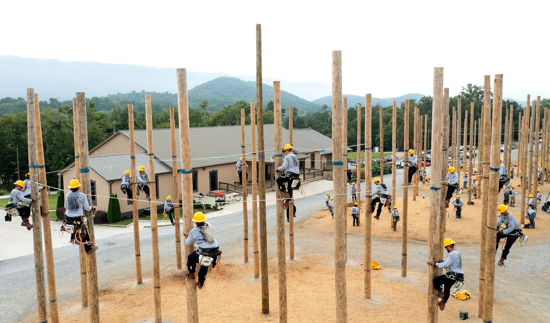 Utility linemen demonstrating professional pole climbing techniques during safety certification training, showcasing industry-standard practices for electrical infrastructure maintenance.