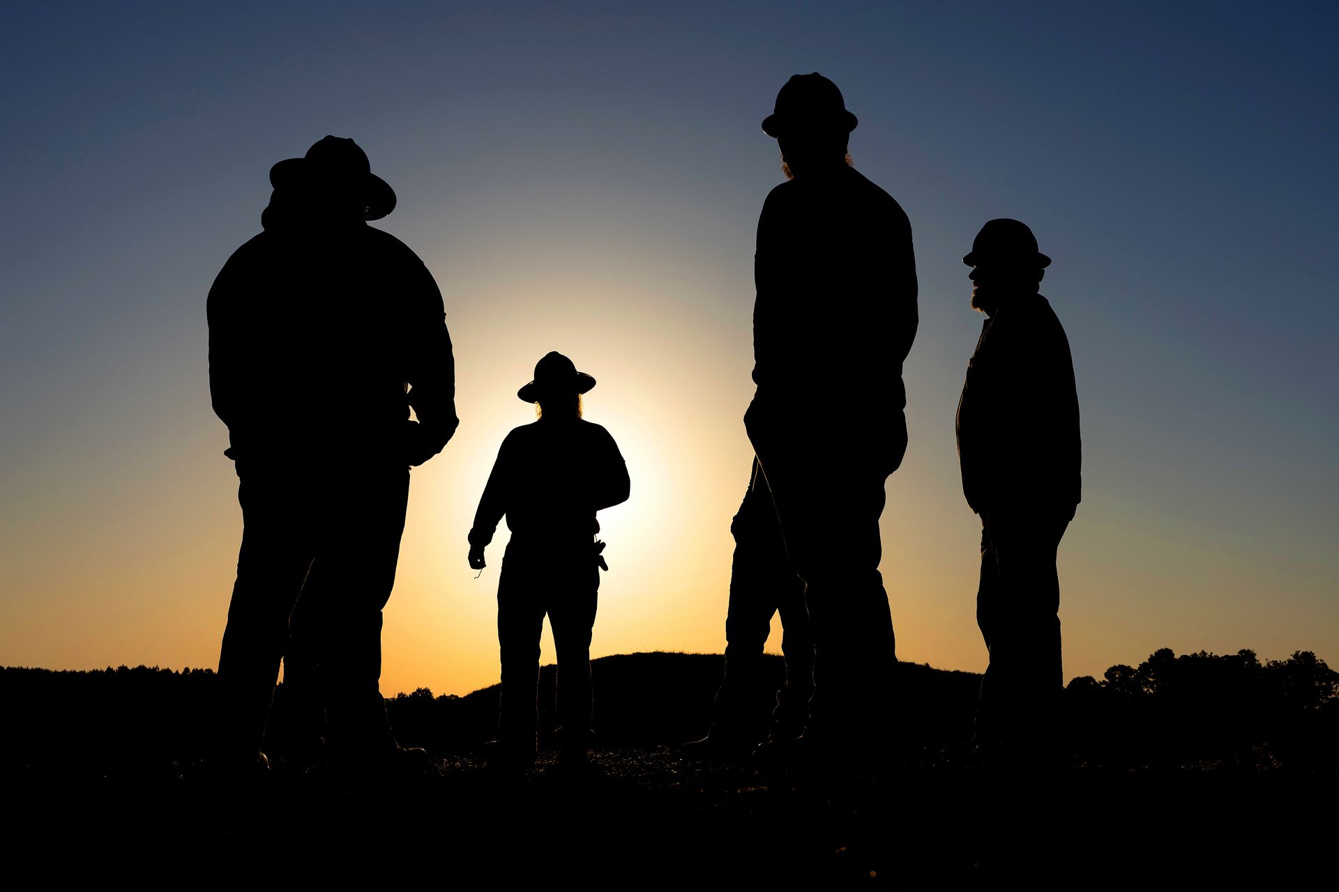 Silhouette for workers during a start-of-day huddle at a construction site. 