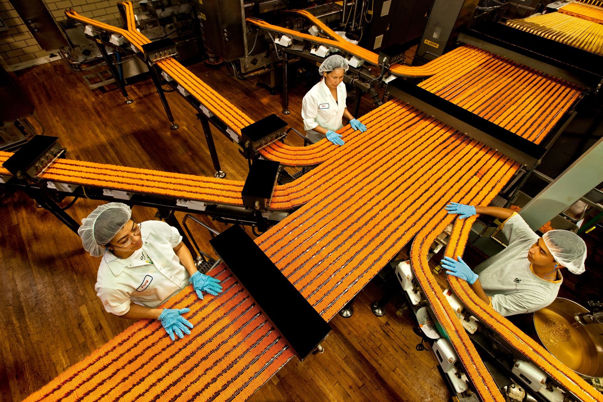 Workers watch over lines of cheese crackers in a food processing plant. 