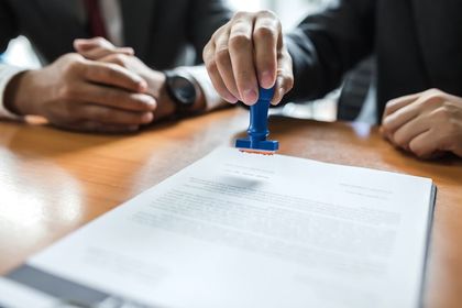 Businessman stamping with approved stamp on document at meeting