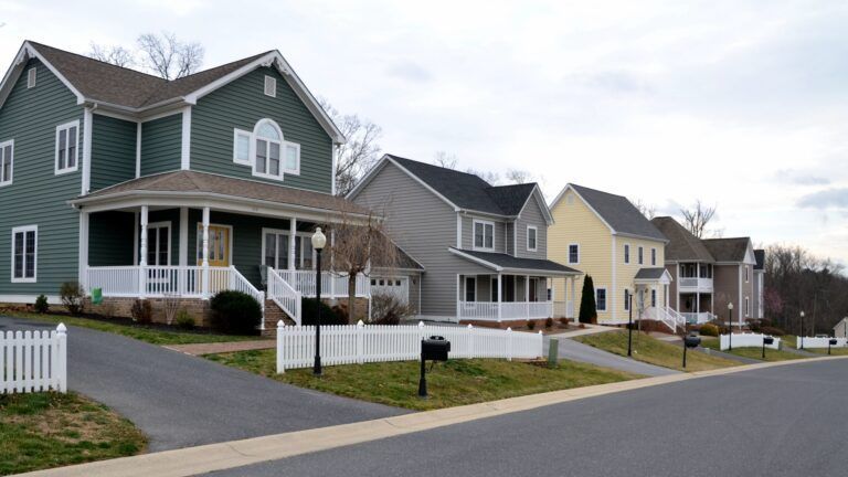 A row of houses in a residential area with a white picket fence.