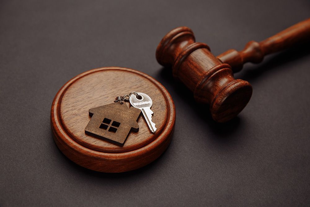 A wooden gavel with a house and keys on it.