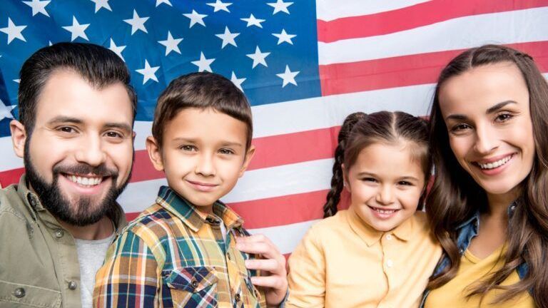 A family is posing for a picture in front of an american flag.