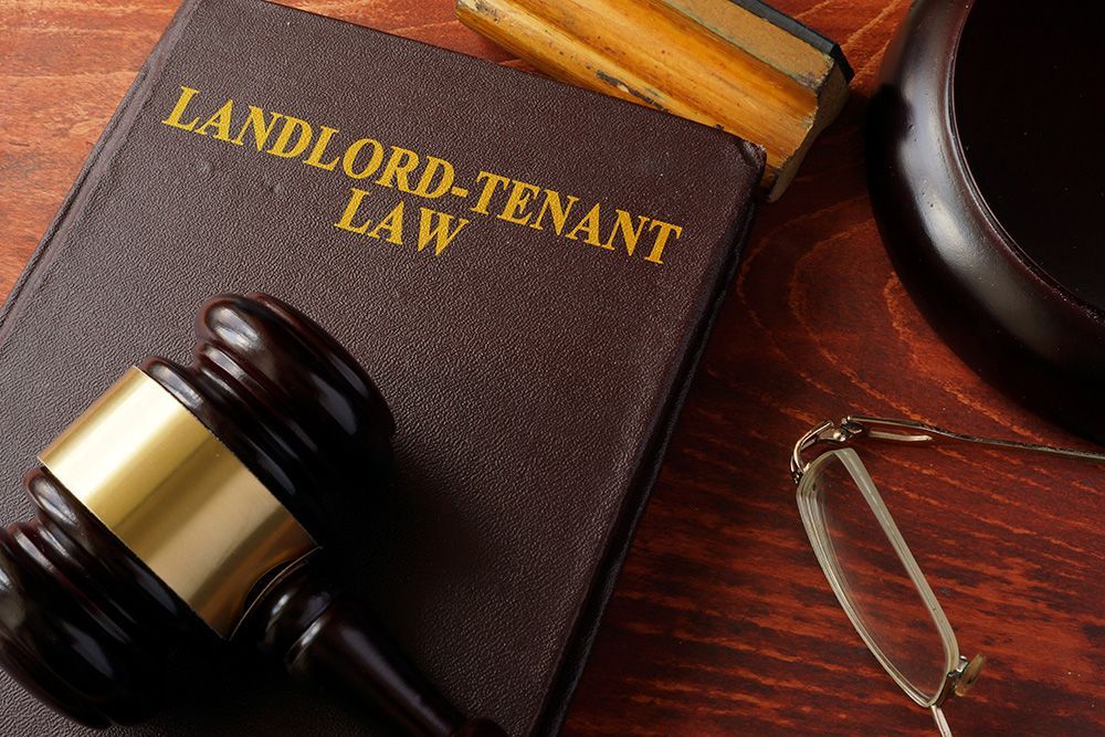A wooden gavel is sitting on top of a book titled landlord-tenant law