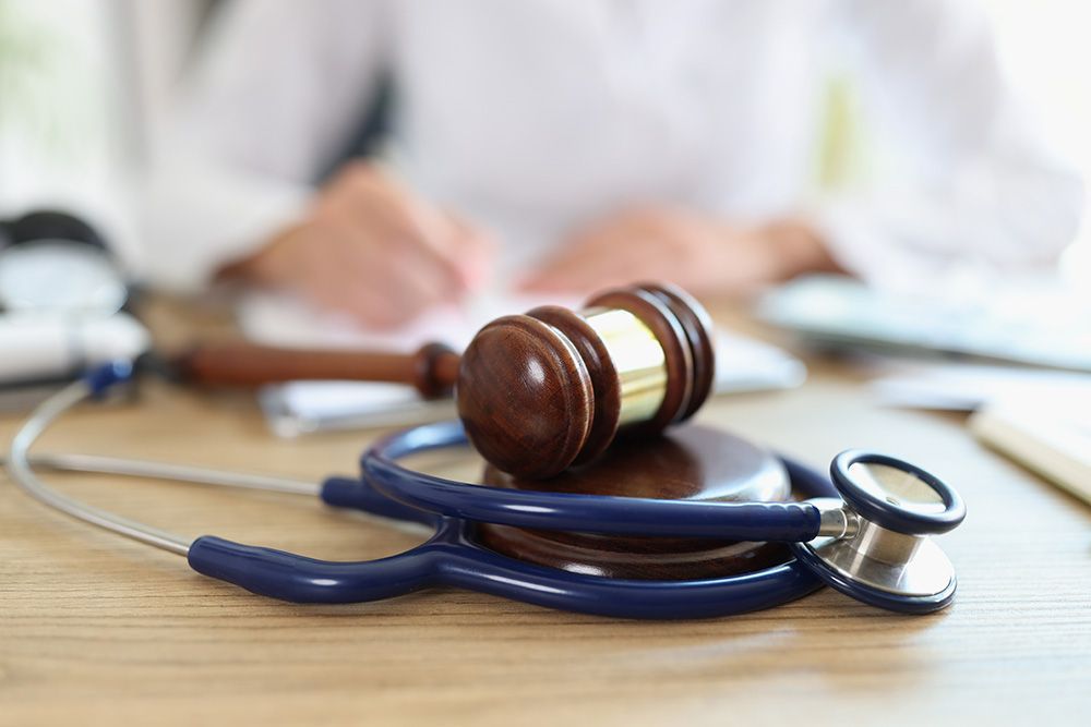 A judge 's gavel and stethoscope are on a wooden table.