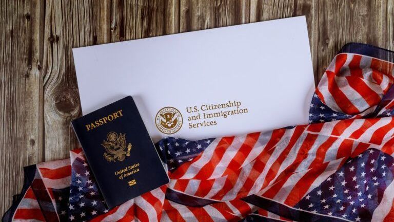 A passport , envelope , and american flag on a wooden table.