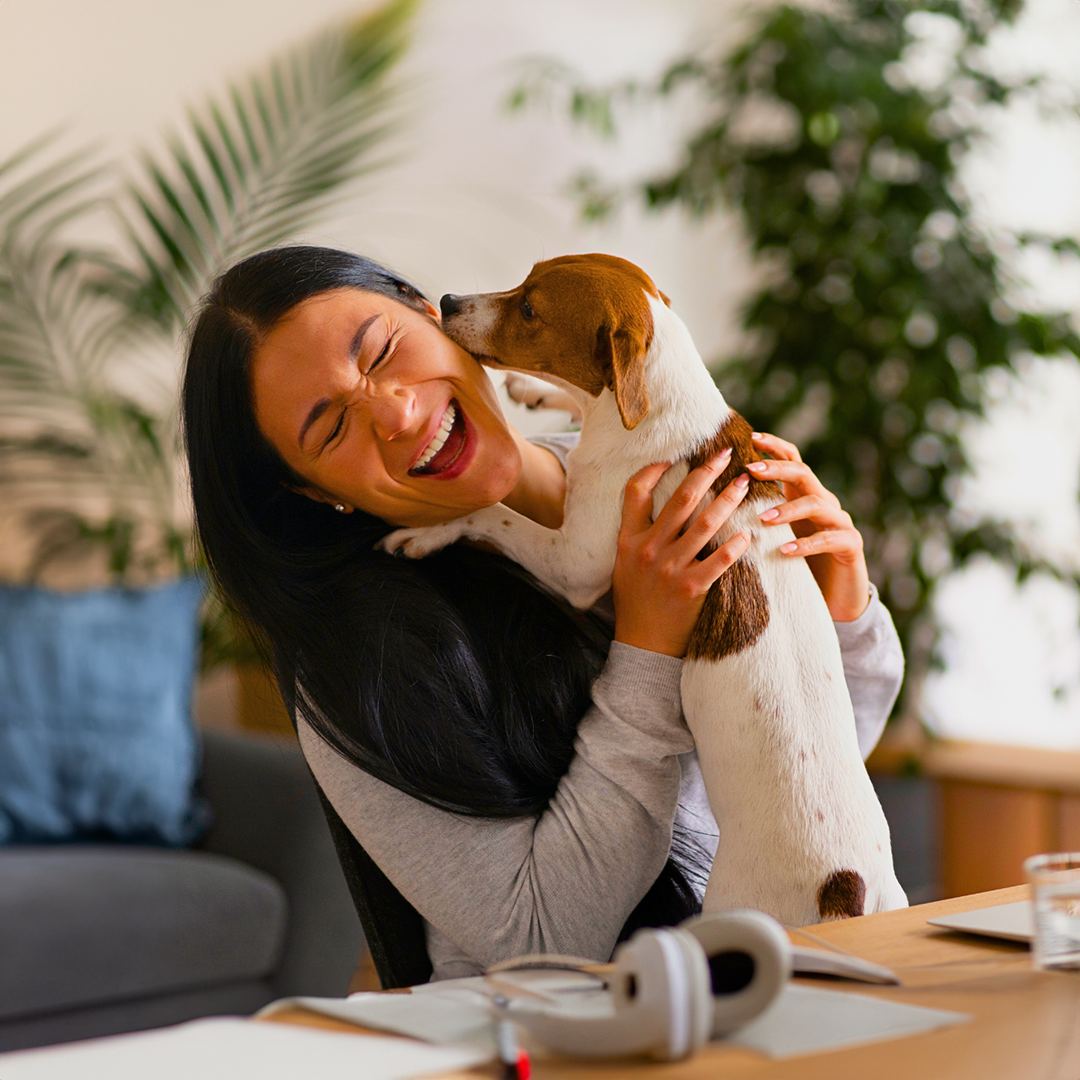 A woman is holding a puppy in her arms and laughing.