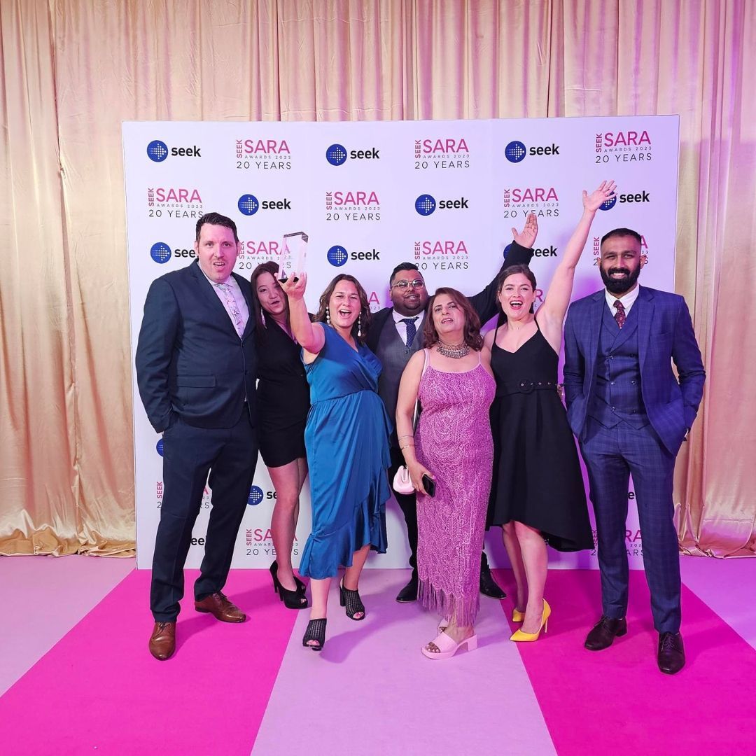 A group of people standing in front of a wall that says isara