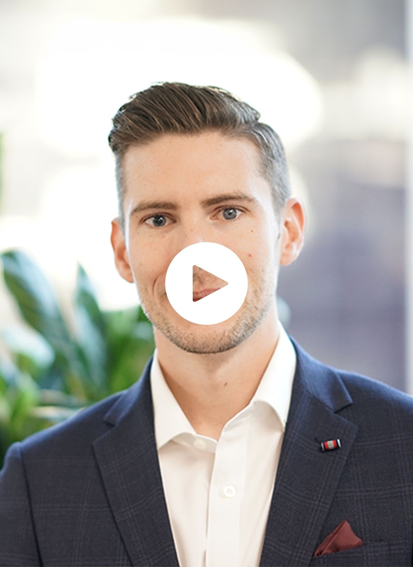 A man in a suit and white shirt has a play button on his face.