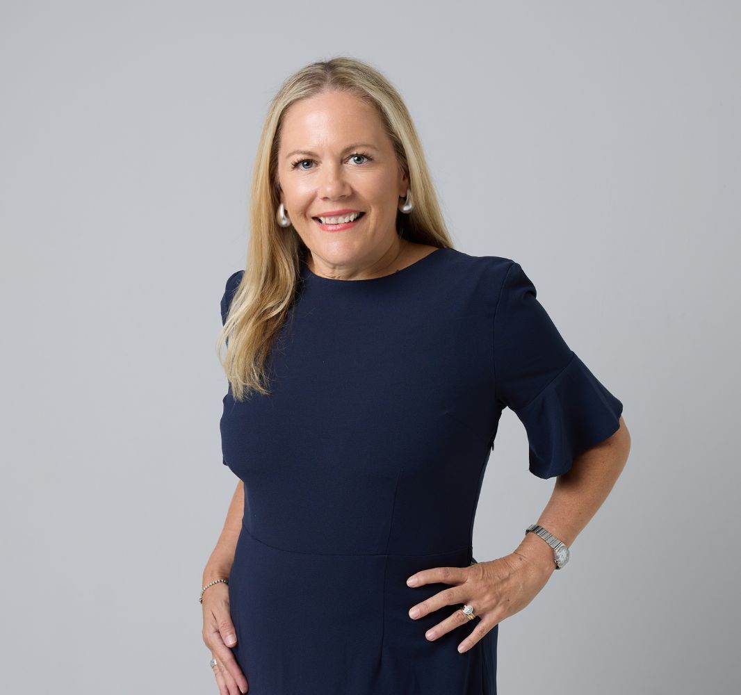 A woman wearing a blue shirt with ruffled sleeves is smiling for the camera.