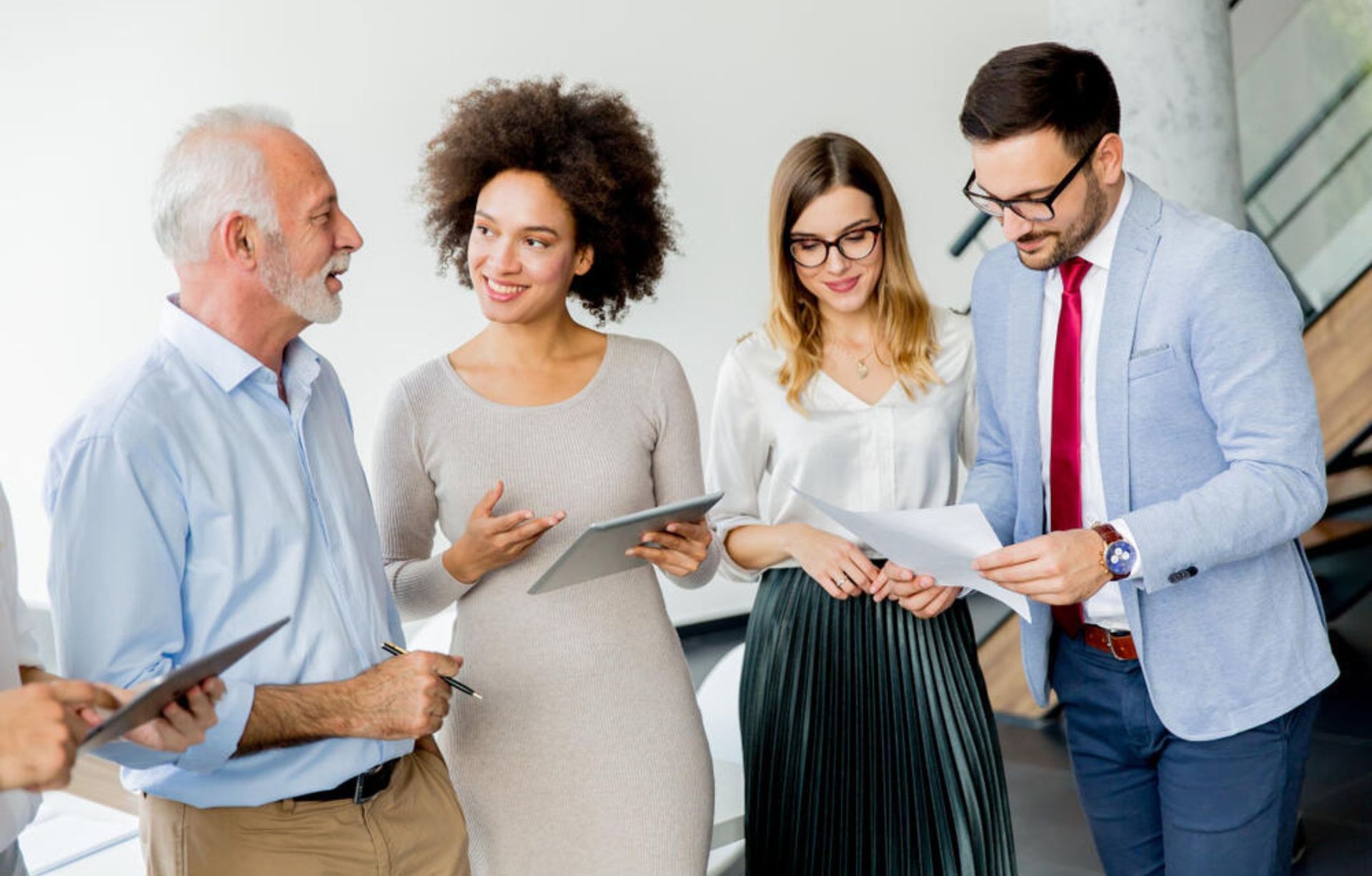 A group of business people are standing next to each other in an office.