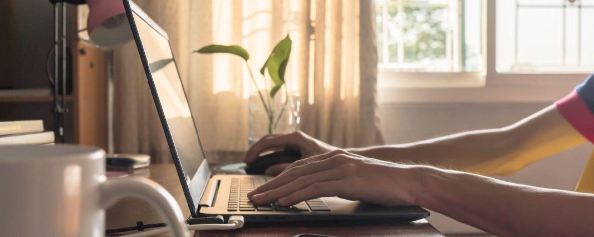 A person is typing on a laptop computer at a desk.