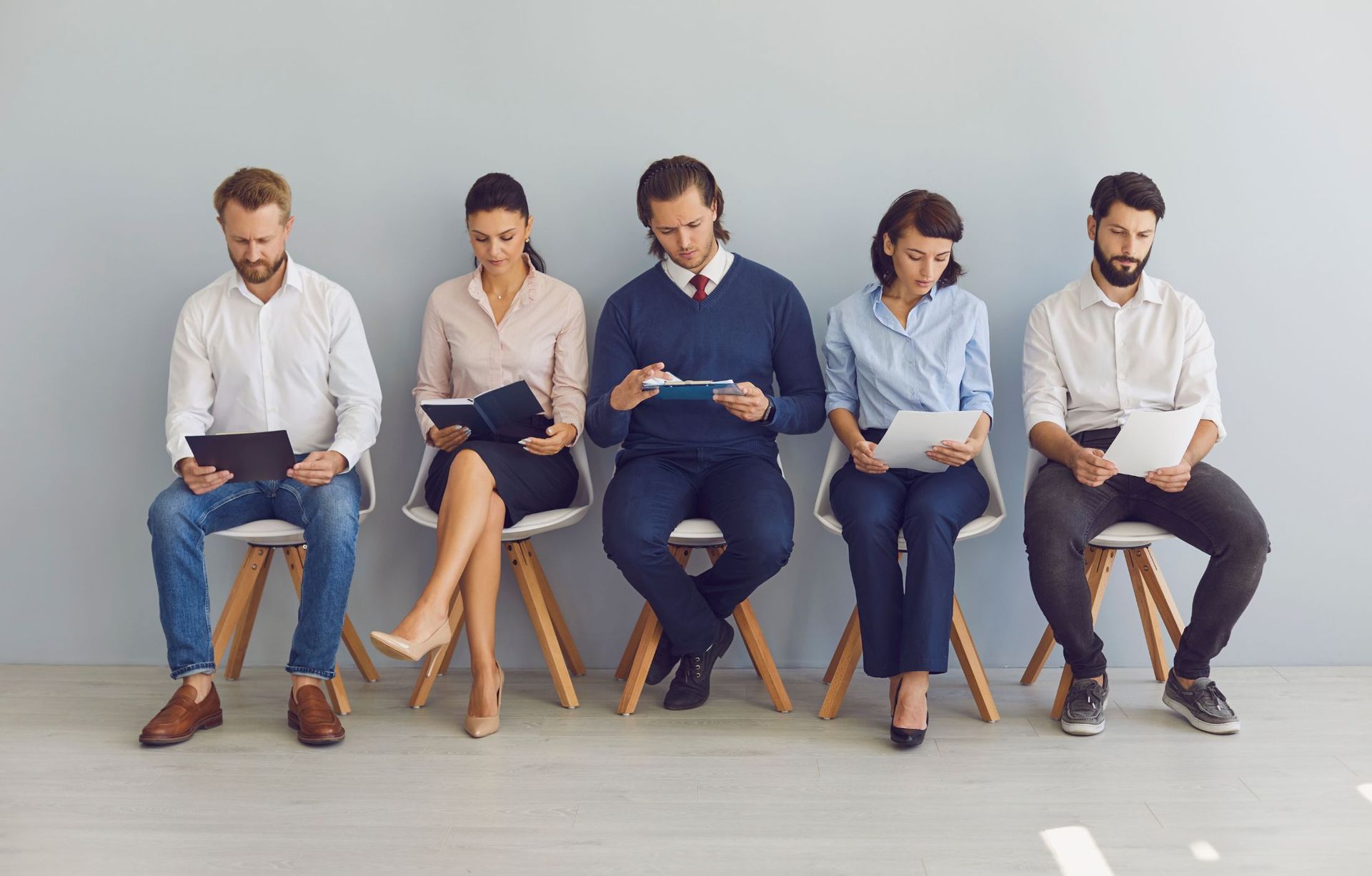 A group of people are sitting in chairs waiting for a job interview.