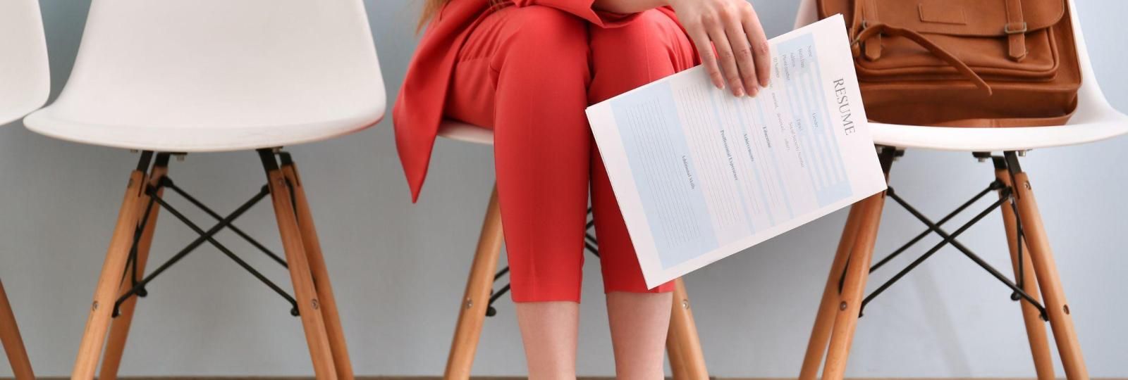 A woman is sitting on a chair holding a piece of paper.