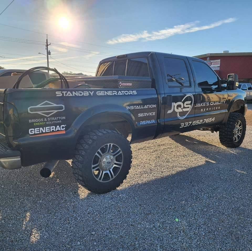 Black lifted pickup truck with sponsor decals parked on gravel in bright sunlight