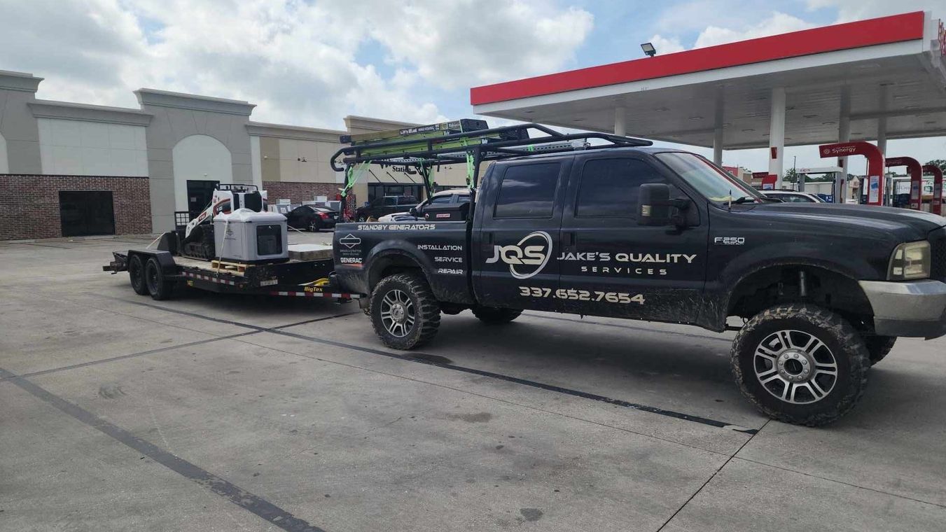 Black pickup truck towing equipment trailer at a gas station, with red canopy in background