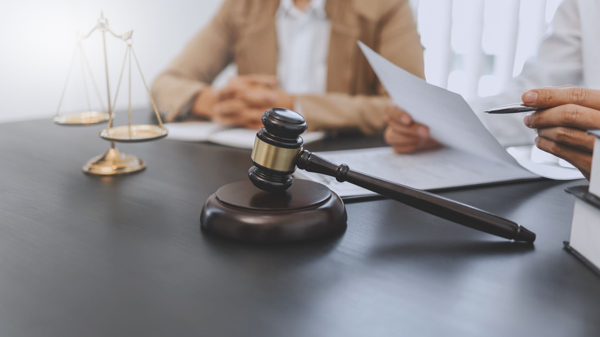 Judge's gavel and scales of justice on desk during legal document review.