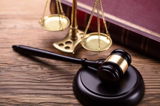 Scales of justice, gavel, and law book on a wooden surface.
