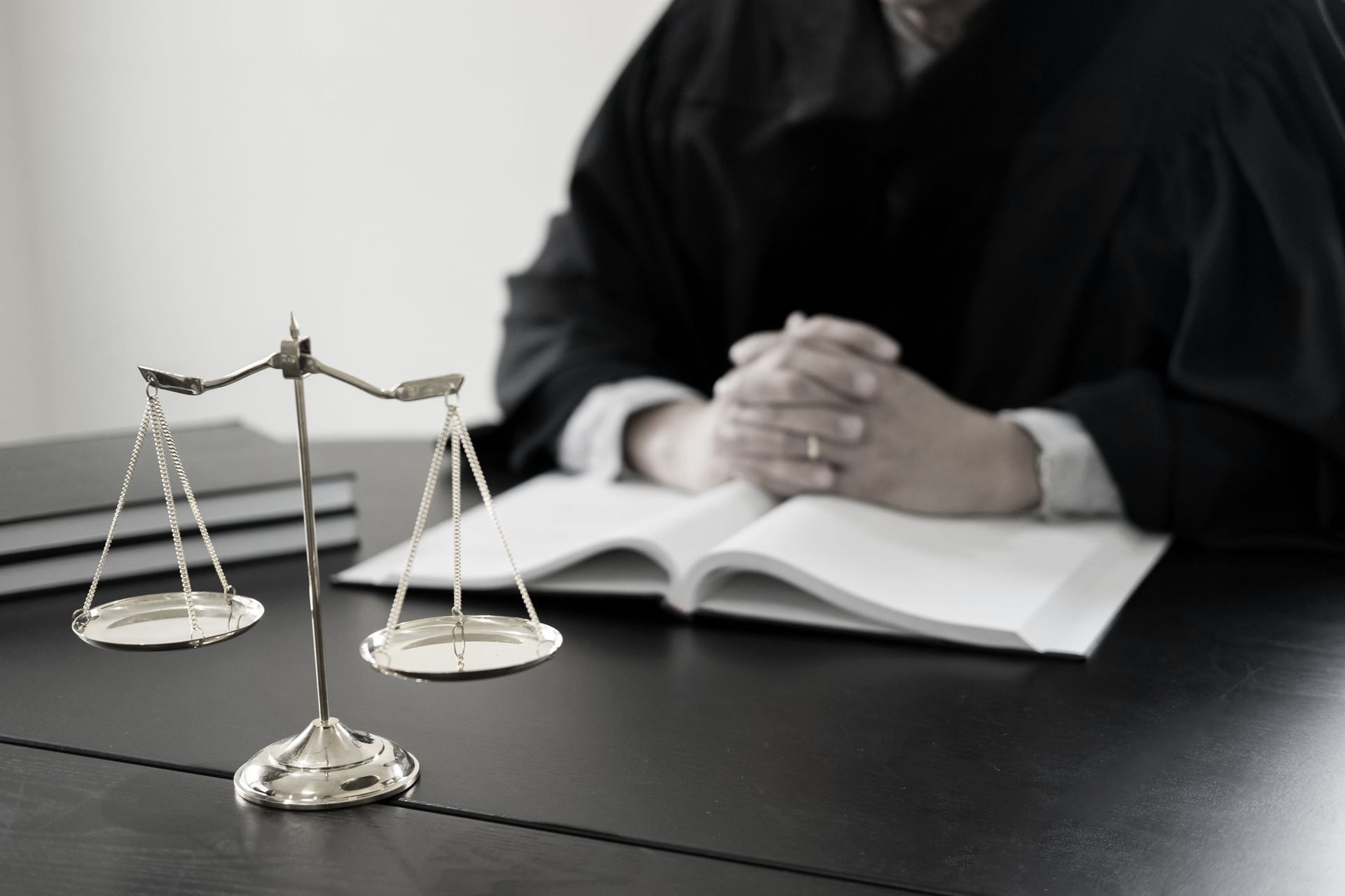 A judge is sitting at a desk with a book and scales of justice