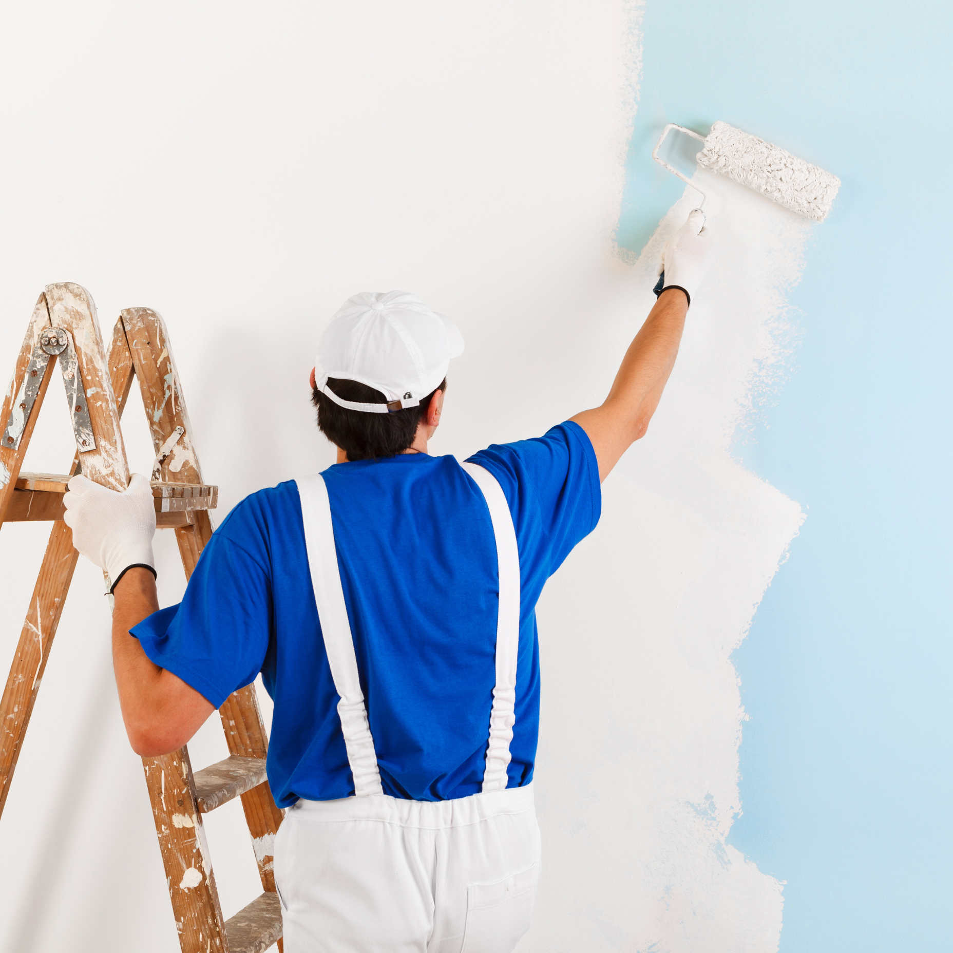 A man is standing on a ladder painting a wall