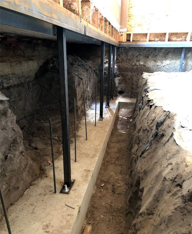 A concrete foundation is being built under a house.