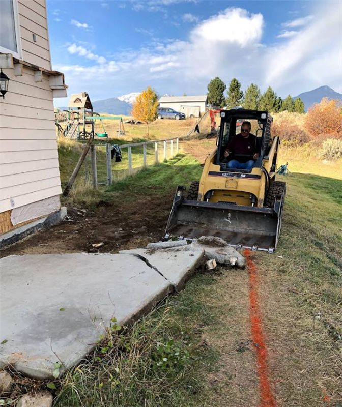 A man is driving a bulldozer in front of a house