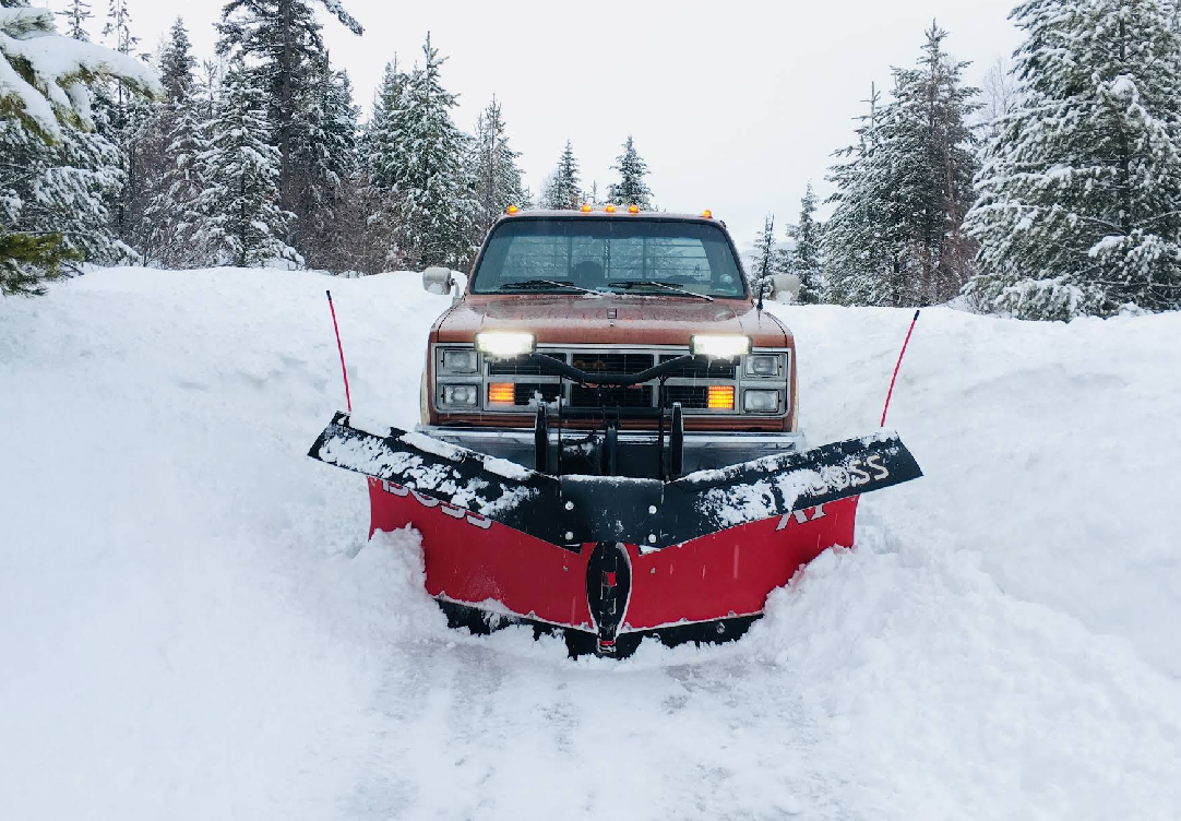 A truck is plowing snow on a snowy road.