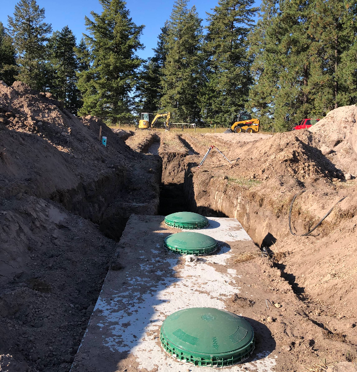 A row of septic tanks are being built in the dirt