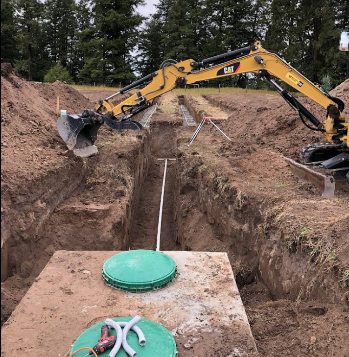 A yellow cat excavator is digging a hole in the dirt