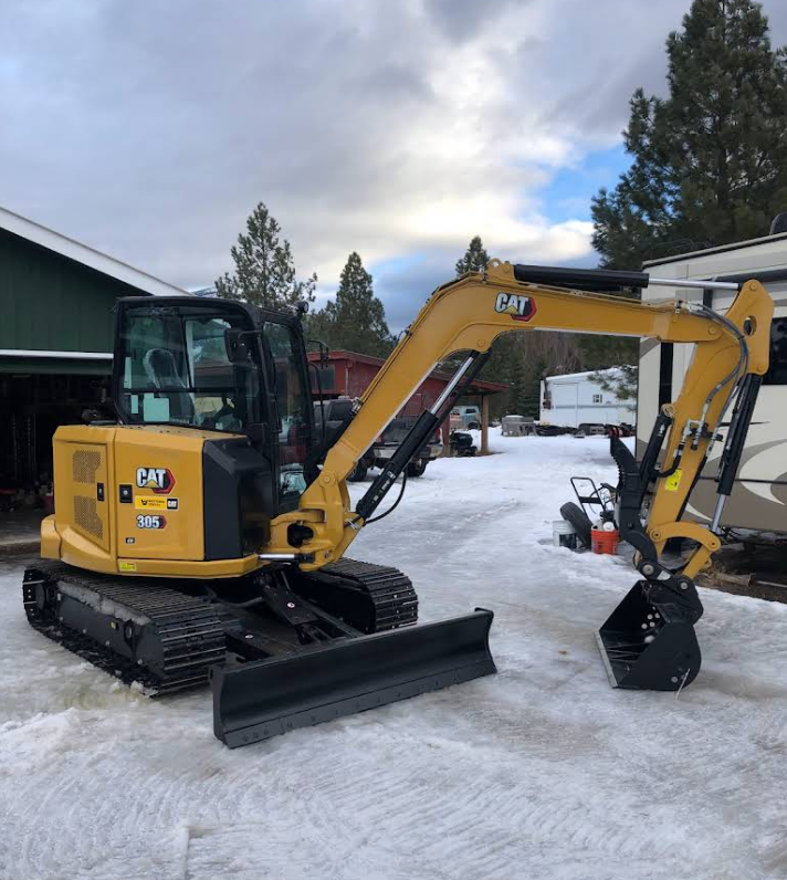 A yellow cat excavator is parked in the snow