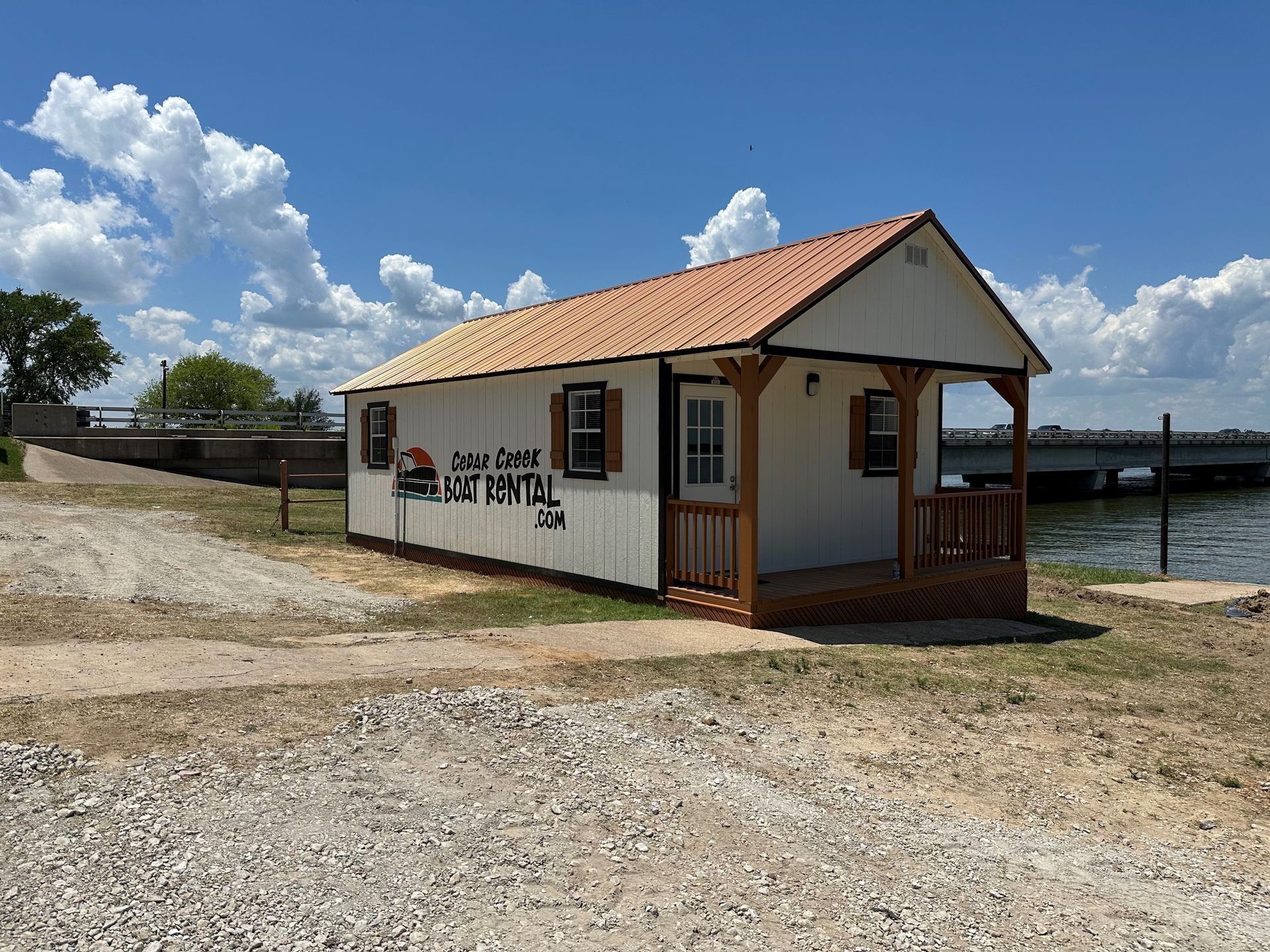 A small white house with a porch next to a body of water.