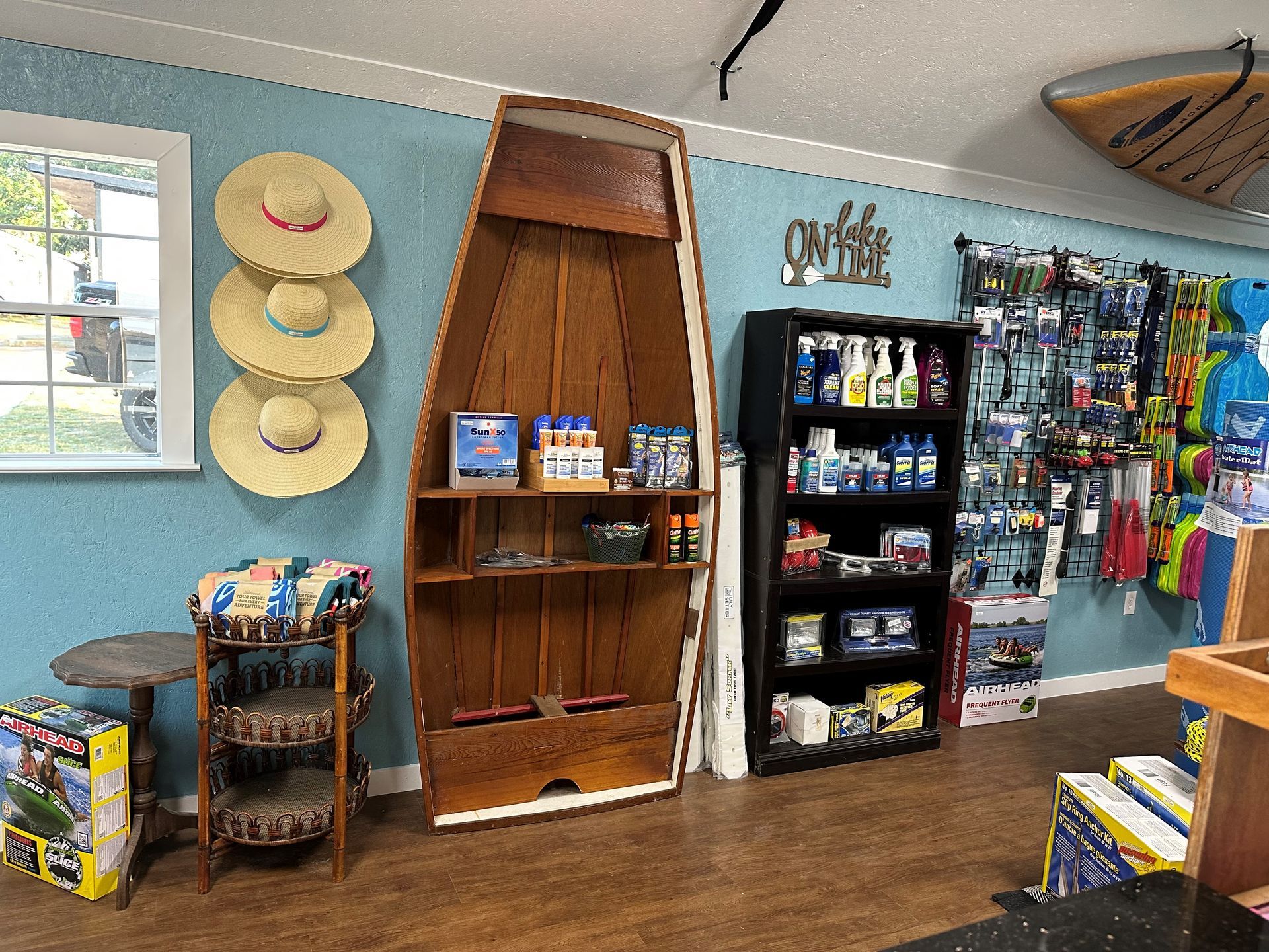 A room with a boat shaped shelf and straw hats hanging on the wall.