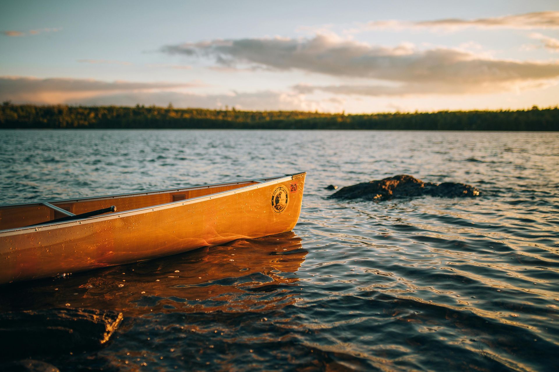 A canoe is sitting on the shore of a lake.