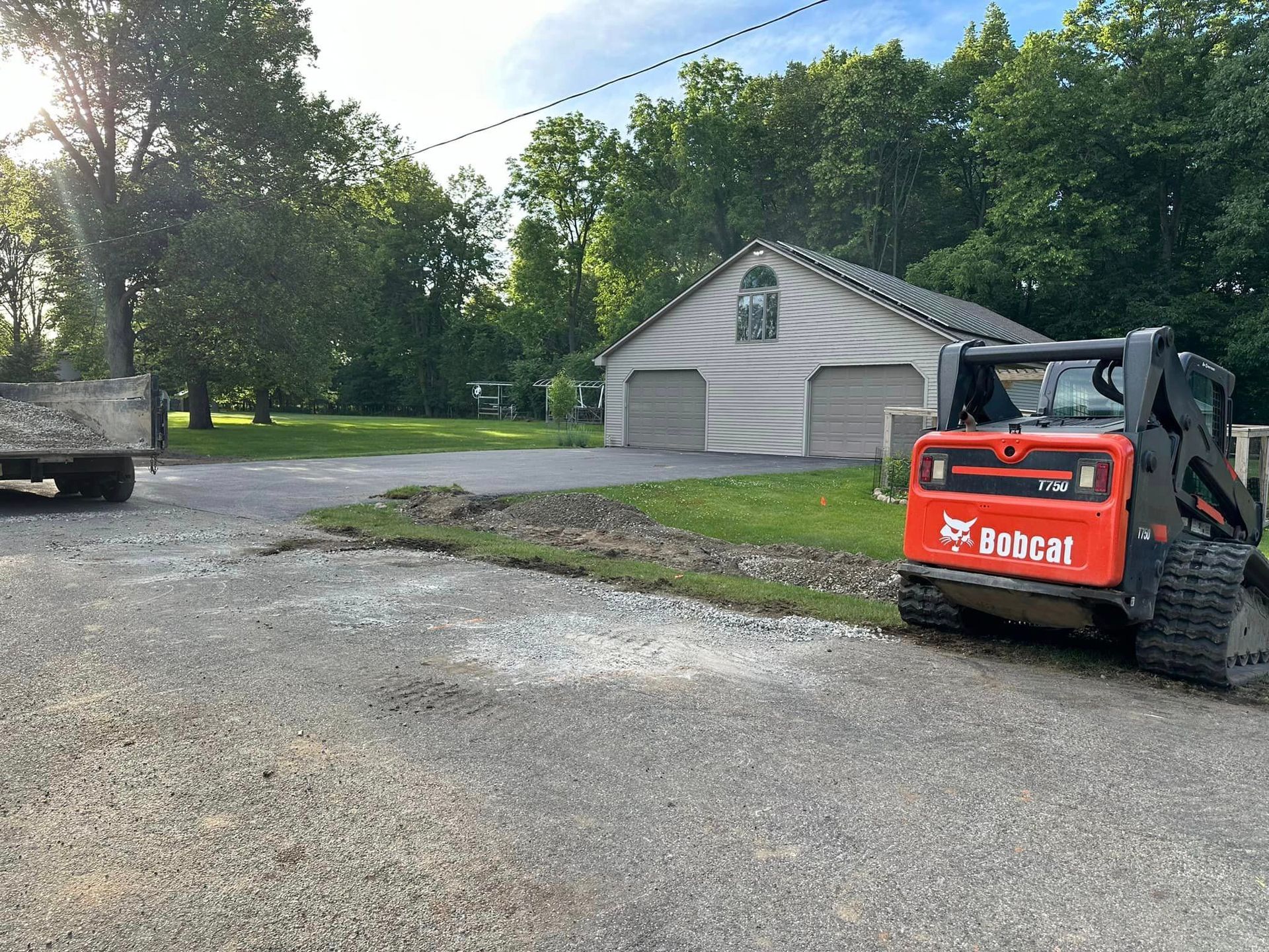 A bobcat tractor is parked in a driveway next to a house.