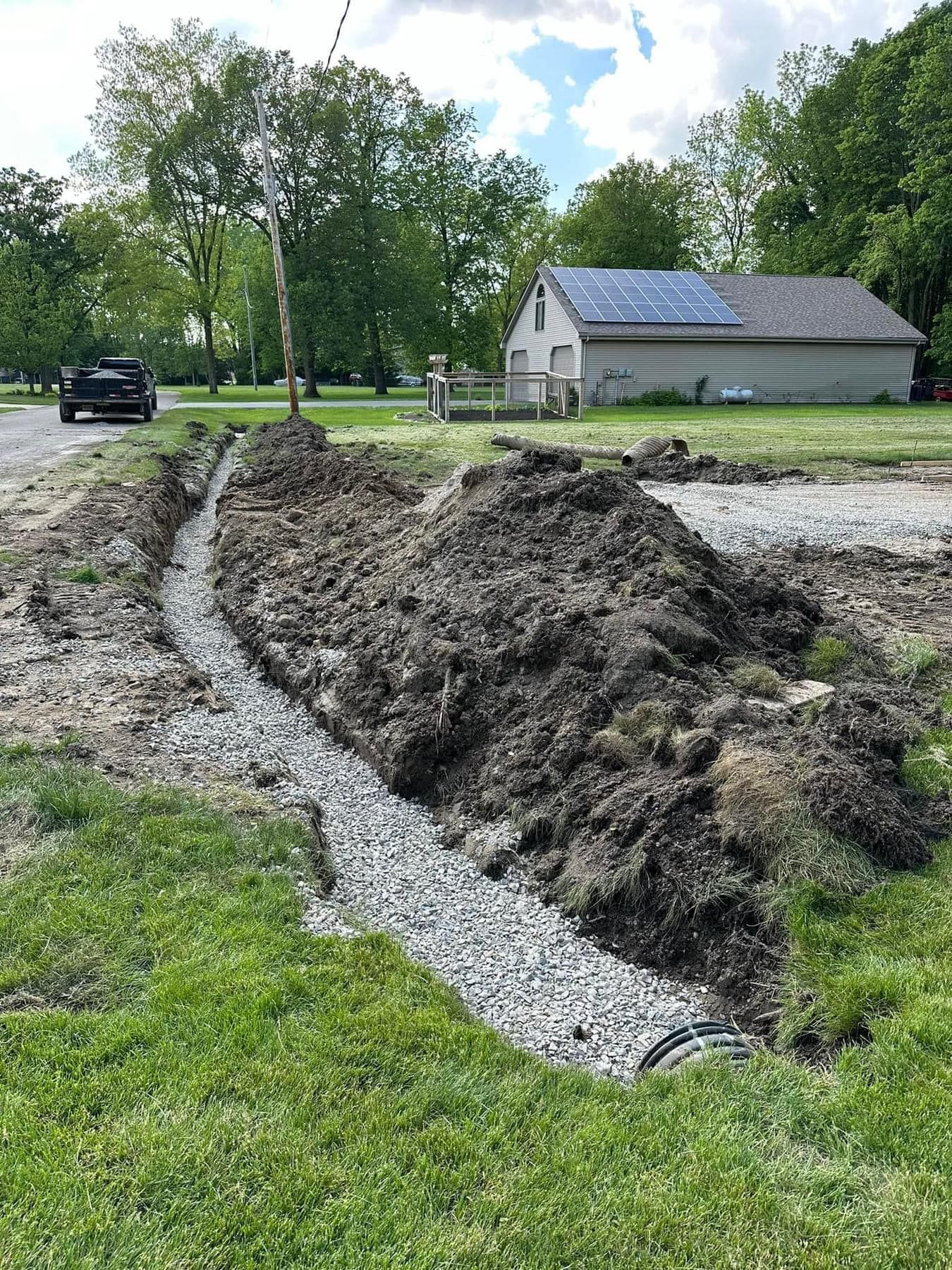 A pile of dirt is sitting on the side of a road next to a house.