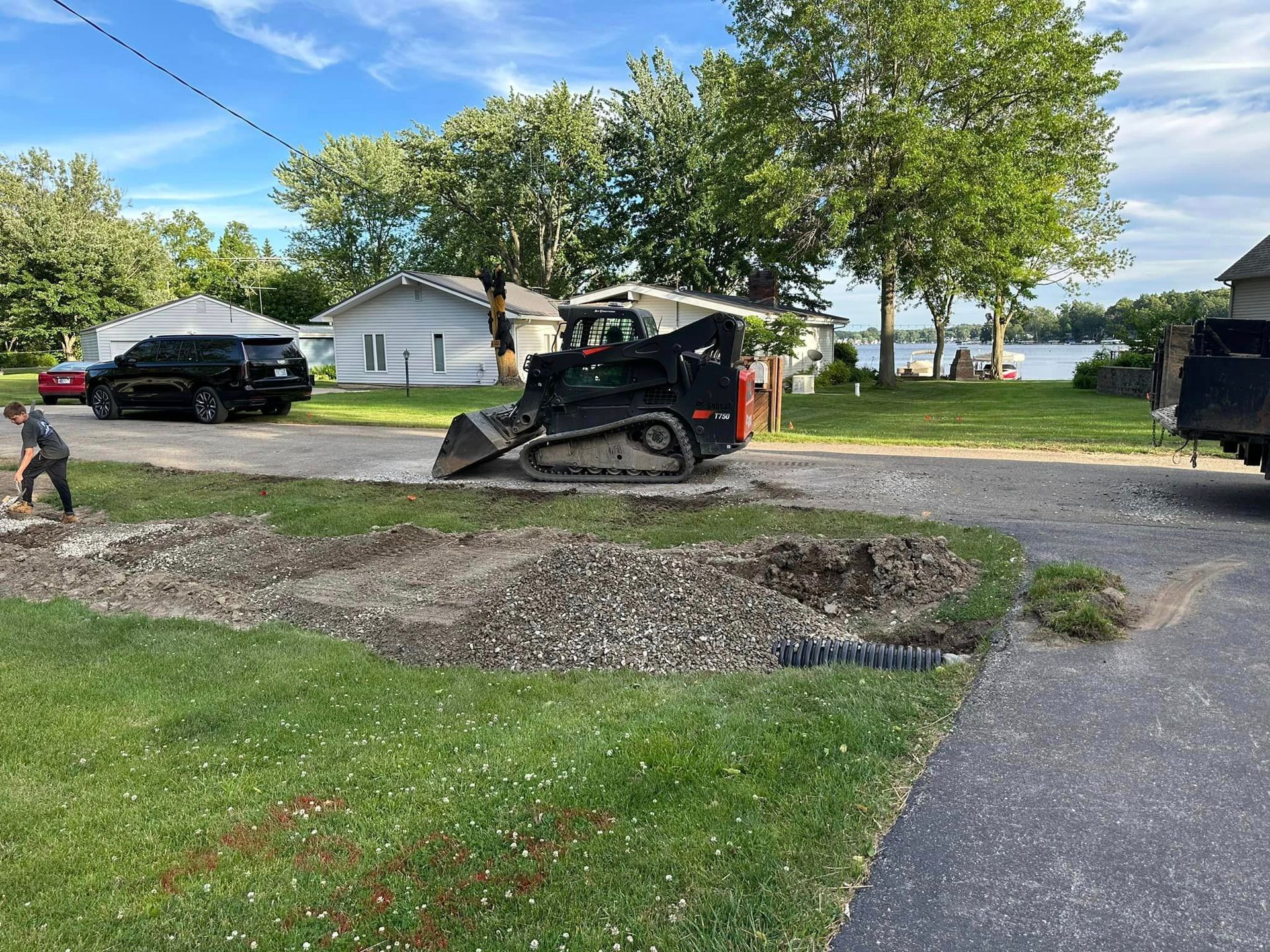 A man is standing next to a bulldozer in a driveway.
