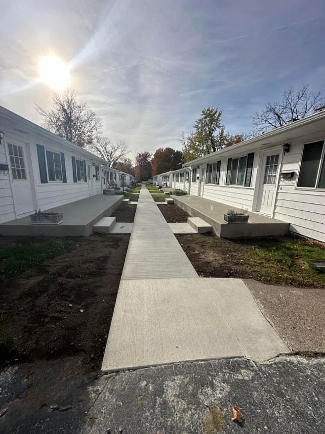 A row of white houses with a concrete walkway between them.