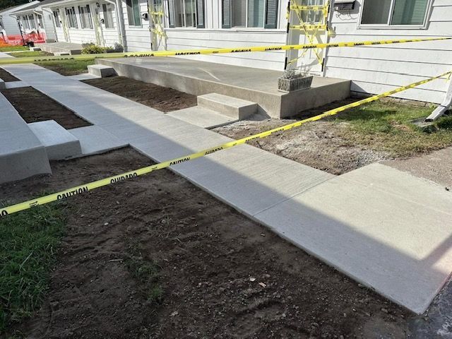 A concrete walkway is being built in front of a house