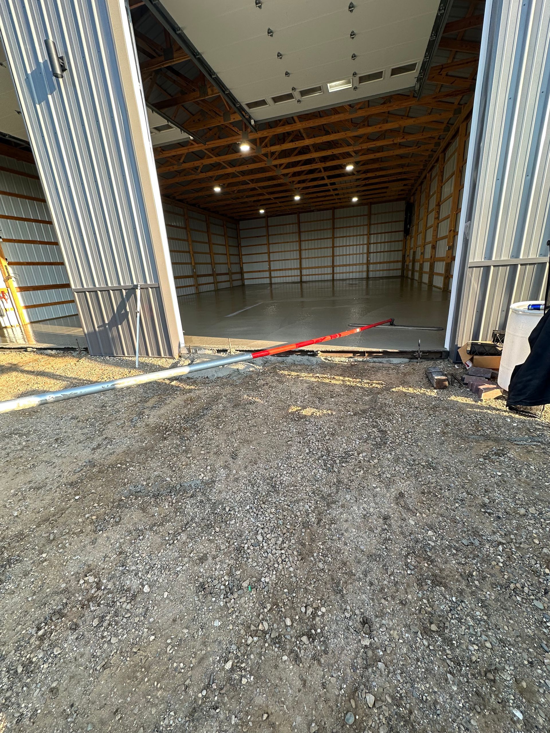 A man is standing in front of a large warehouse with its doors open.