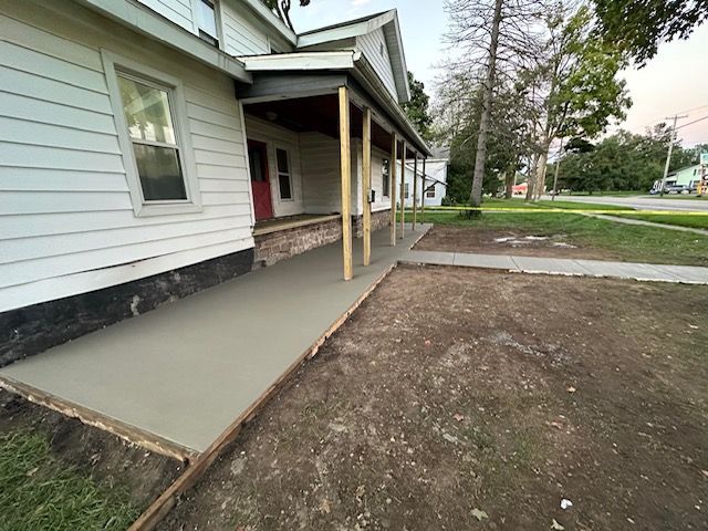 A concrete walkway is being built in front of a house.