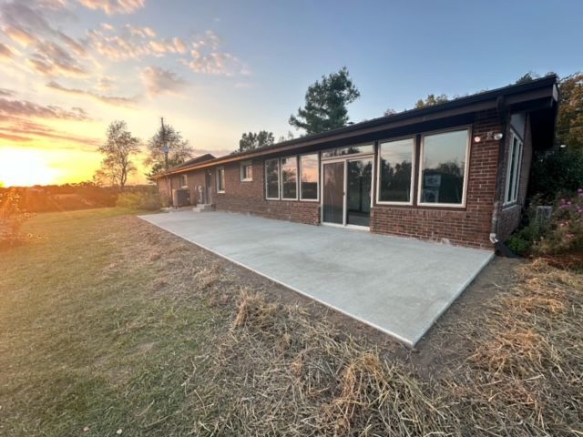 A large brick house with a concrete patio in front of it.