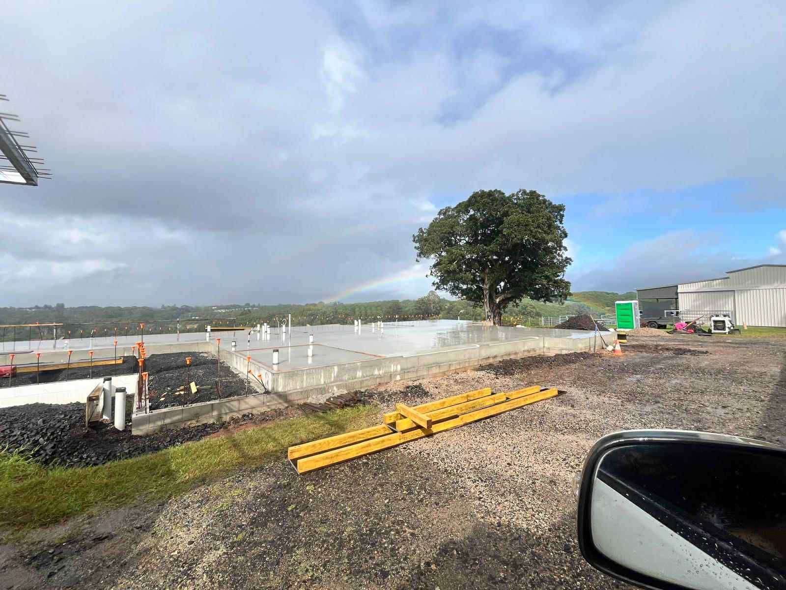 A car is parked in front of a construction site with a rainbow in the sky — ZBM Constructions in Wollongbar, NSW