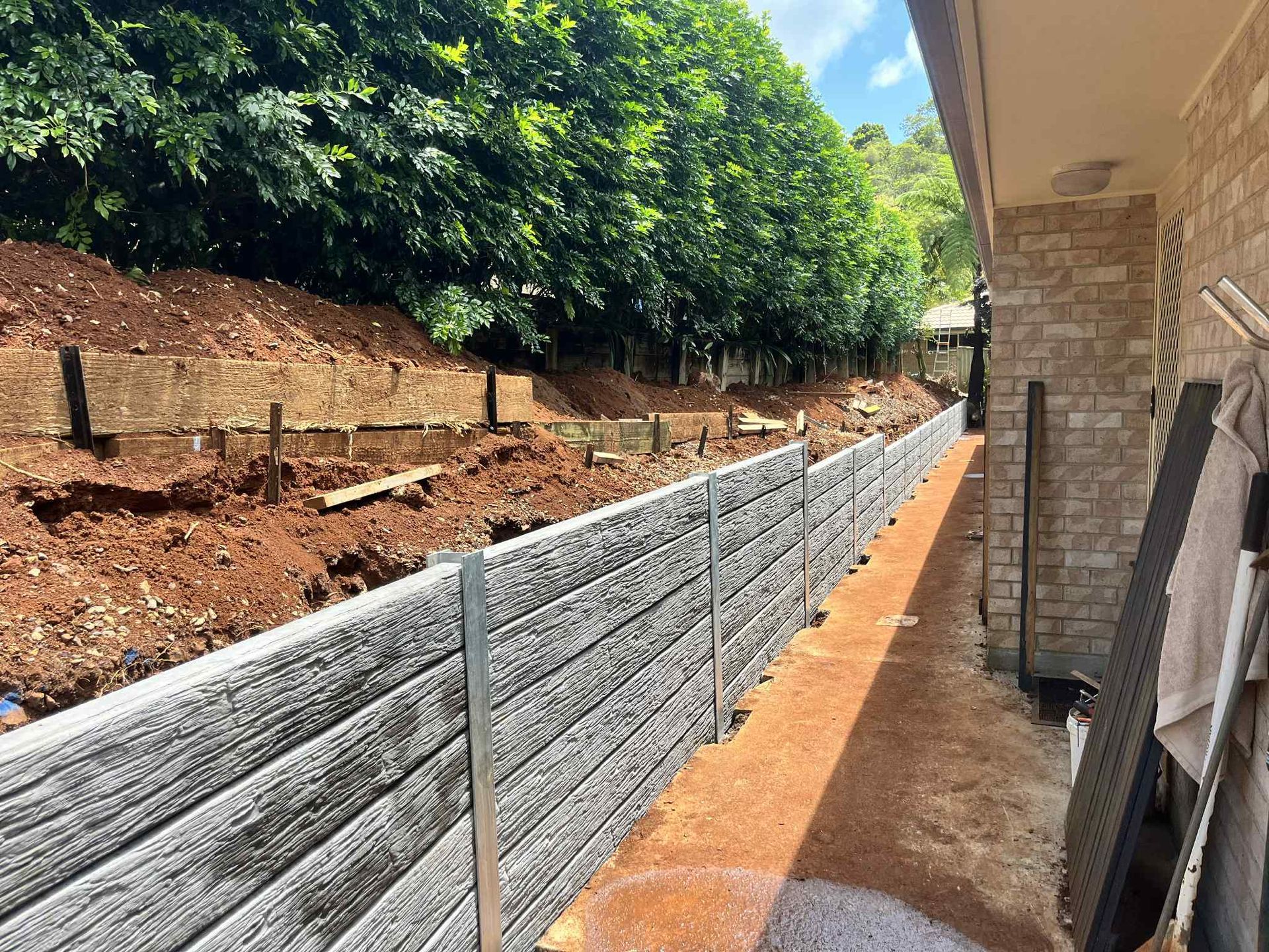 A concrete wall is being built next to a brick building — ZBM Constructions in Wollongbar, NSW
