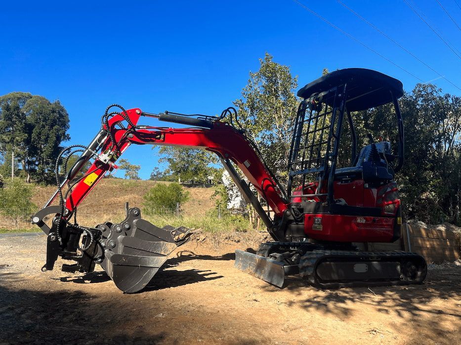 A Red and Black Excavator Is Parked on The Side of The Road — ZBM Constructions in Wollongbar, NSW