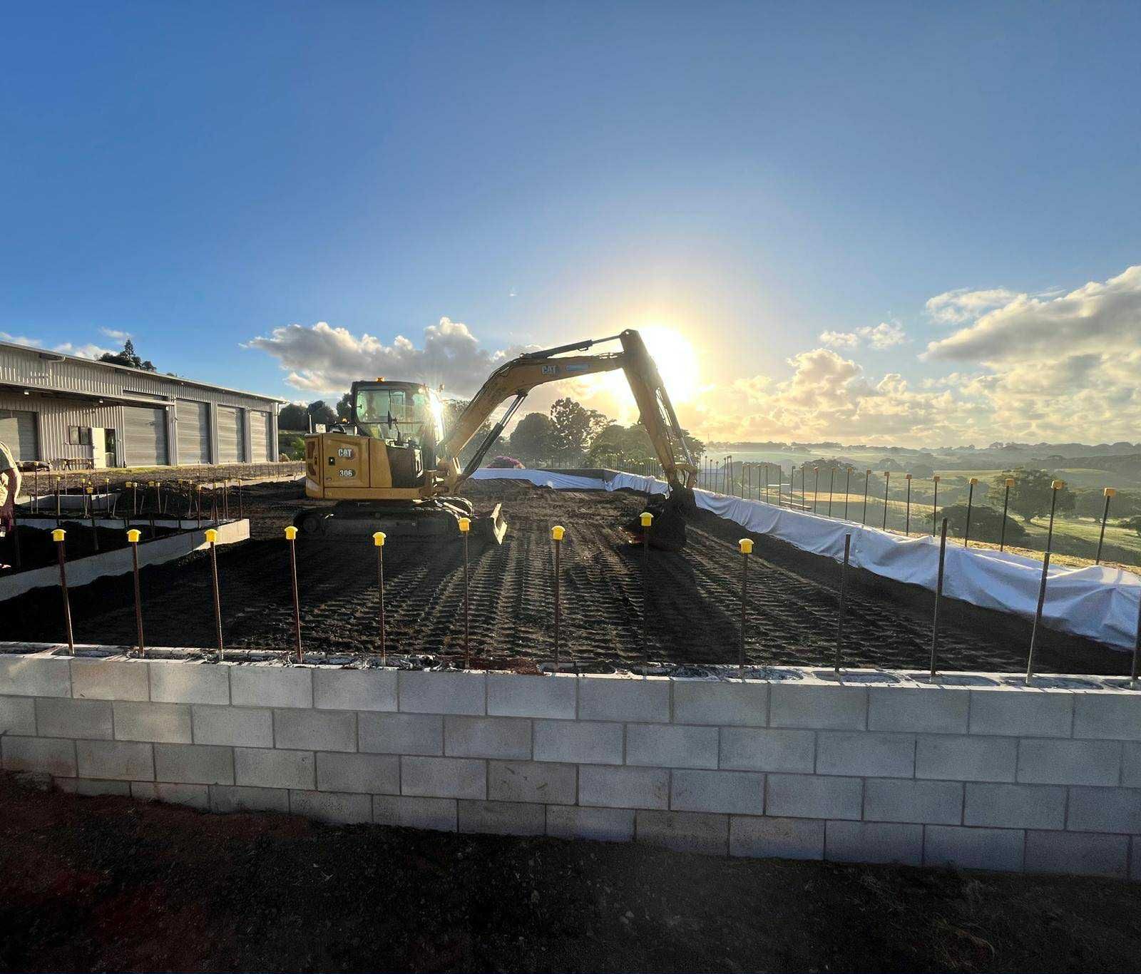 A large yellow excavator is working on a construction site — ZBM Constructions in Wollongbar, NSW